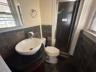 bathroom with tile walls, a wealth of natural light, and a shower stall