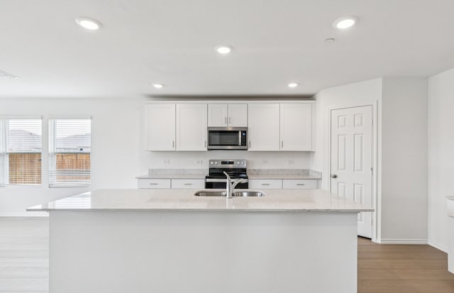 7200 Pederson Creek Way, Denton, TX 76208 - kitchen featuring appliances with stainless steel finishes, a sink, light stone countertops, light wood finished floors, and white cabinetry