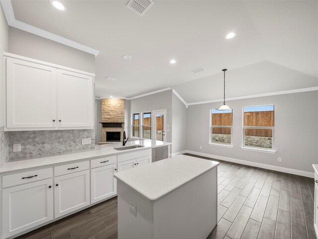 kitchen featuring visible vents, crown molding, open floor plan, and a sink