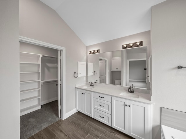 full bathroom featuring lofted ceiling, a sink, wood tiled floor, and double vanity