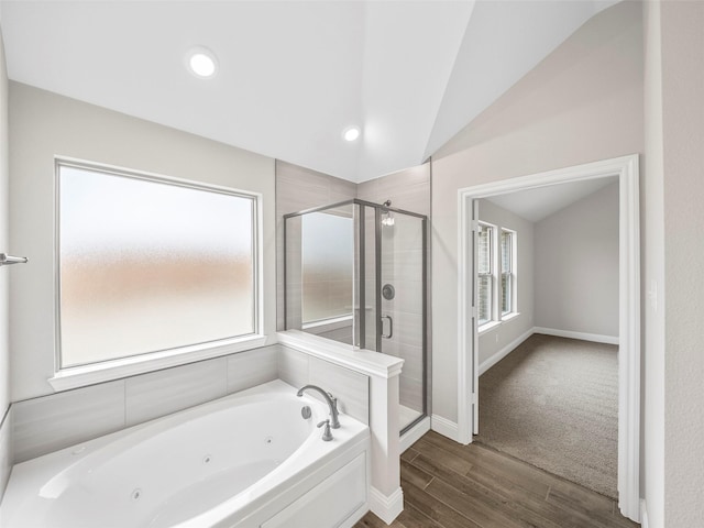 bathroom with lofted ceiling, wood finished floors, a tub with jets, baseboards, and a stall shower
