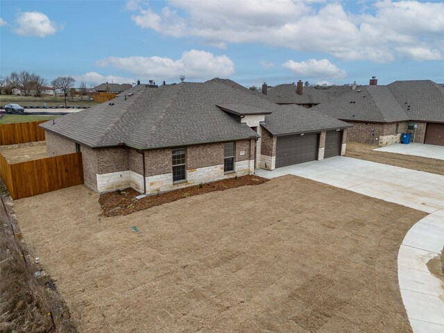 view of front of home with fence, concrete driveway, brick siding, roof with shingles, and a garage
