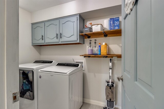 laundry area featuring washing machine and dryer, baseboards, and cabinet space