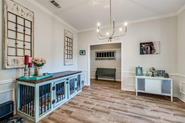 dining space featuring wood finished floors, visible vents, crown molding, and a notable chandelier