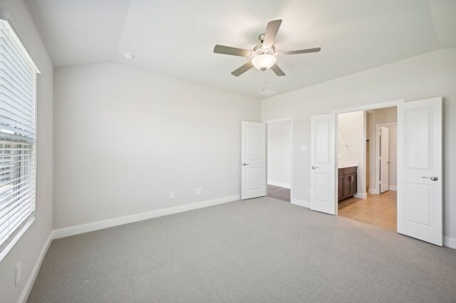 unfurnished bedroom with vaulted ceiling, a ceiling fan, baseboards, and light carpet