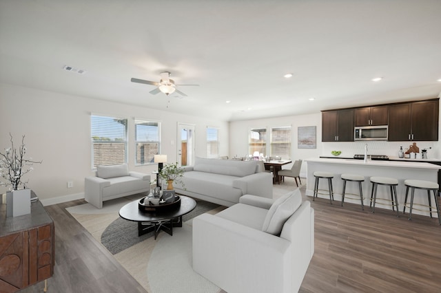 living room featuring light wood-style flooring, visible vents, a wealth of natural light, and ceiling fan