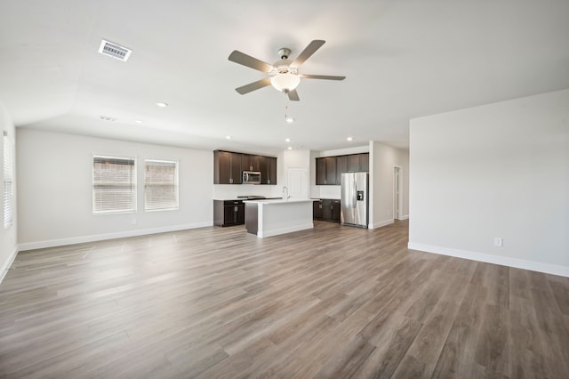 unfurnished living room with visible vents, light wood finished floors, baseboards, and ceiling fan