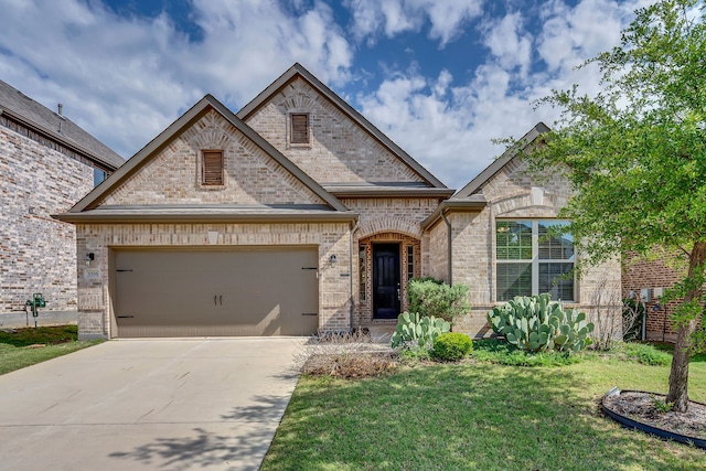 french provincial home with a garage, brick siding, a front yard, and driveway