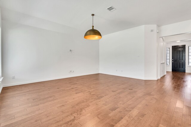unfurnished room featuring baseboards, visible vents, and light wood-style flooring