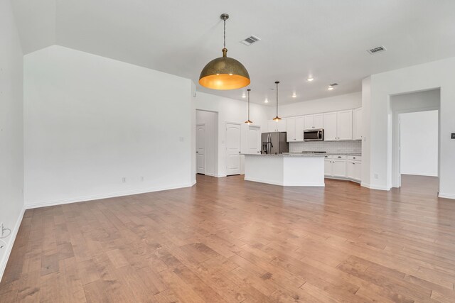 unfurnished living room with baseboards, visible vents, and light wood-type flooring