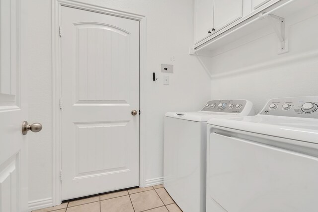 laundry area with light tile patterned floors, cabinet space, and washing machine and clothes dryer