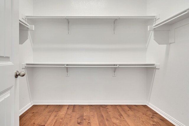 walk in closet with wood finished floors