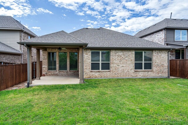 rear view of house with a patio, a yard, a fenced backyard, a ceiling fan, and roof with shingles