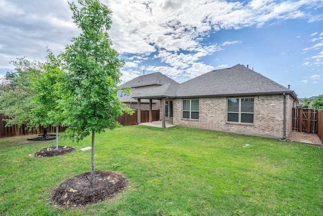 back of house with a patio area, a shingled roof, a yard, brick siding, and a fenced backyard