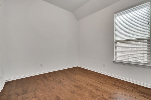 empty room featuring dark wood finished floors, baseboards, and vaulted ceiling