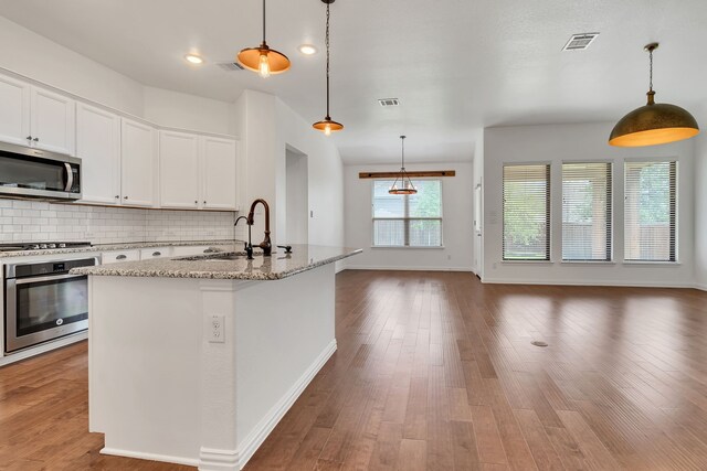 kitchen featuring decorative backsplash, a sink, visible vents, stainless steel appliances, and open floor plan