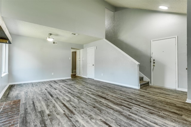 unfurnished living room with visible vents, baseboards, wood finished floors, and stairs