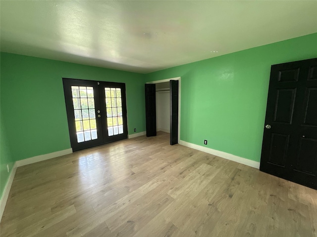 unfurnished bedroom featuring french doors, baseboards, light wood-style floors, and a closet