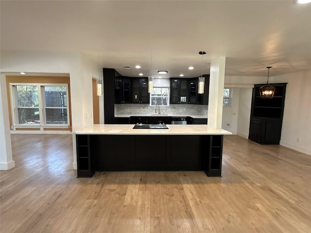 kitchen featuring a peninsula, light wood-style floors, and dark cabinetry