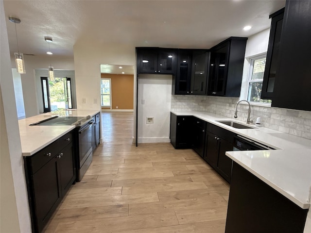 kitchen featuring light wood-type flooring, dark cabinets, black / electric stove, and a sink