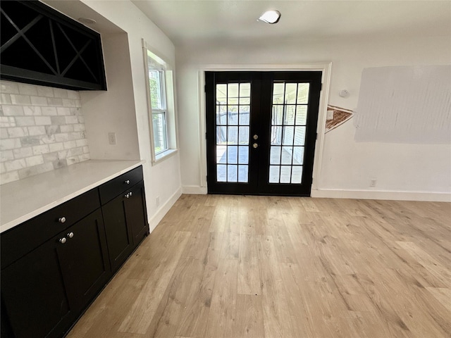 doorway to outside with baseboards, light wood-style floors, and french doors