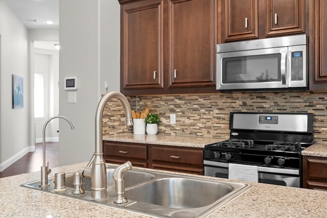 4717 Whitehall Ct, Mckinney, TX 75070 - kitchen featuring stainless steel appliances, a sink, decorative backsplash, dark brown cabinetry, and recessed lighting