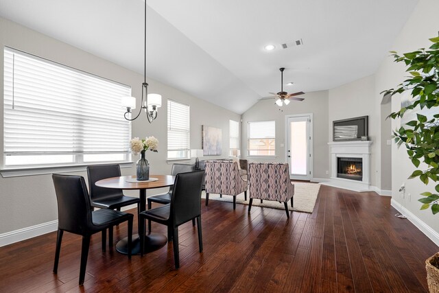 4717 Whitehall Ct, Mckinney, TX 75070 - dining room featuring dark wood-style floors, a ceiling fan, a warm lit fireplace, vaulted ceiling, and a chandelier