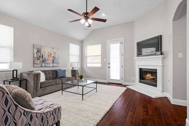 4717 Whitehall Ct, Mckinney, TX 75070 - living area featuring ceiling fan, dark wood-type flooring, a warm lit fireplace, baseboards, and vaulted ceiling