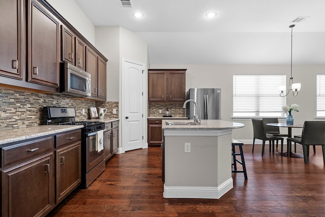 4717 Whitehall Ct, Mckinney, TX 75070 - kitchen with appliances with stainless steel finishes, a sink, dark brown cabinetry, backsplash, and a center island with sink