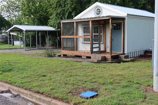 view of front facade featuring an outdoor structure, a carport, metal roof, and a front yard