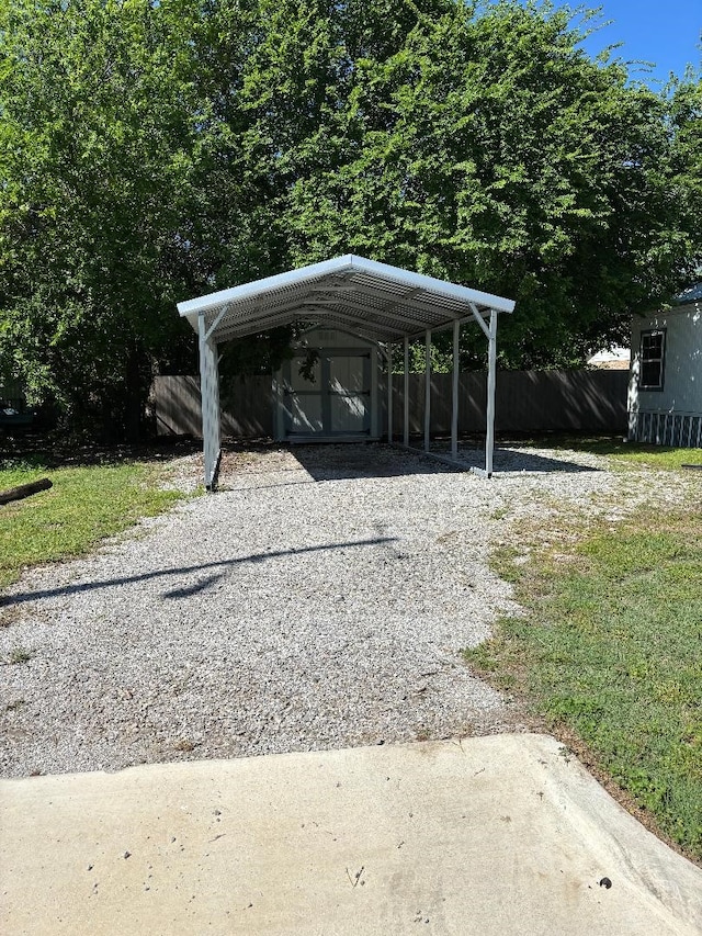view of parking / parking lot with a detached carport, driveway, and fence