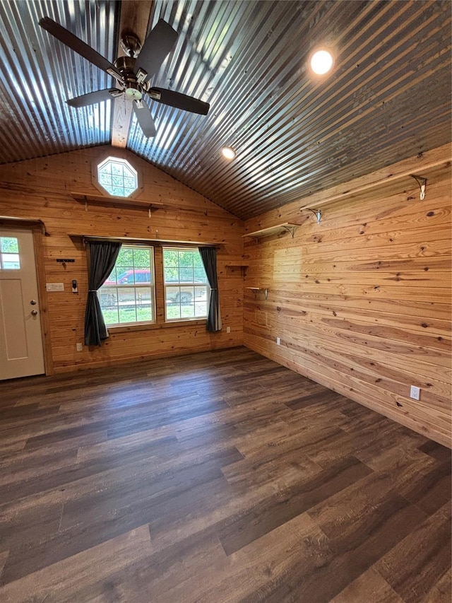 interior space with vaulted ceiling, wood walls, ceiling fan, and wood finished floors