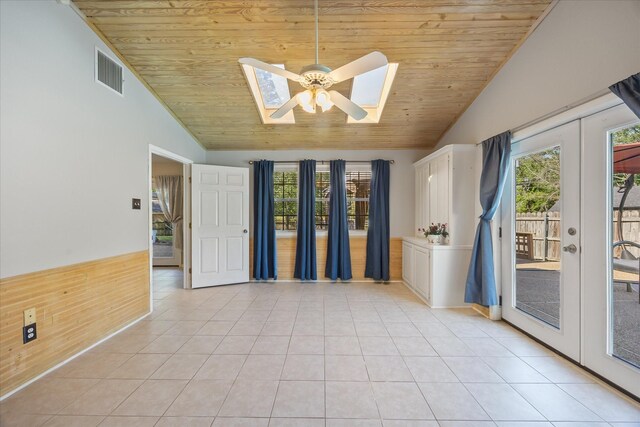 unfurnished room with lofted ceiling with skylight, visible vents, light tile patterned floors, and wood ceiling