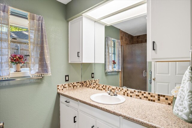 full bath with a stall shower, vanity, and tasteful backsplash