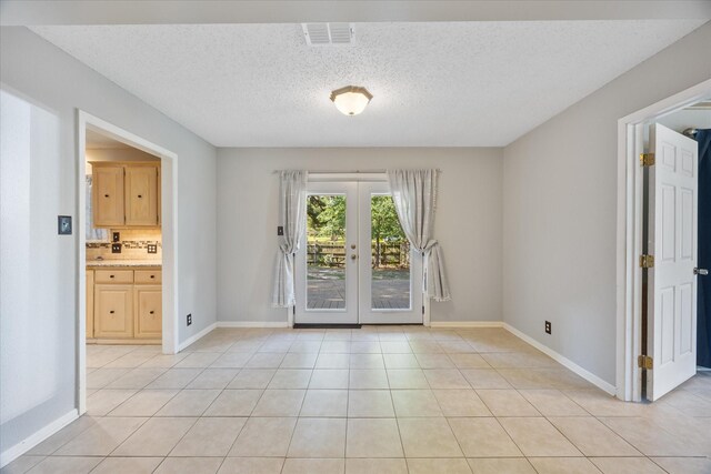 unfurnished room featuring french doors, baseboards, visible vents, a textured ceiling, and light tile patterned flooring