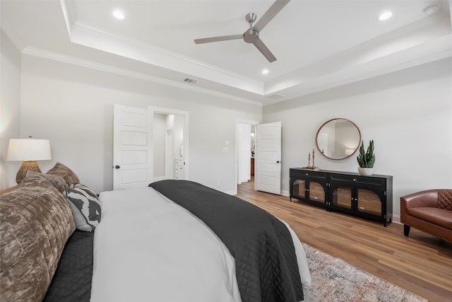 bedroom featuring recessed lighting, a raised ceiling, wood finished floors, and ornamental molding