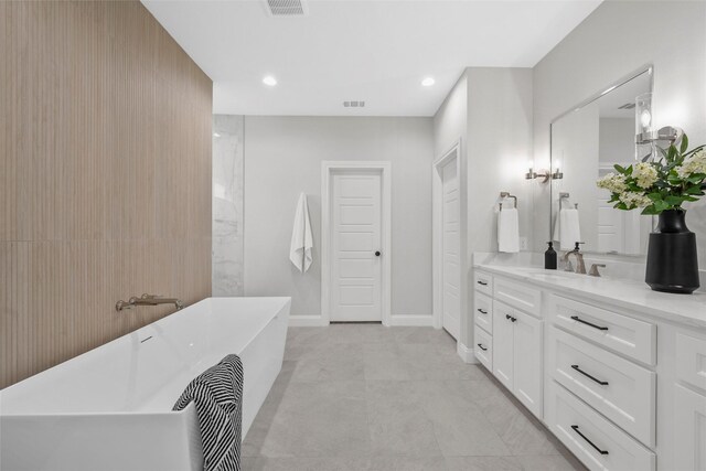 full bathroom with recessed lighting, a freestanding bath, visible vents, vanity, and baseboards