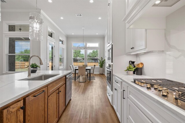 kitchen with a sink, brown cabinets, light wood finished floors, appliances with stainless steel finishes, and recessed lighting