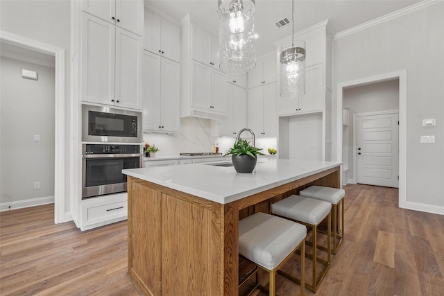 kitchen featuring baseboards, appliances with stainless steel finishes, and light wood-style flooring