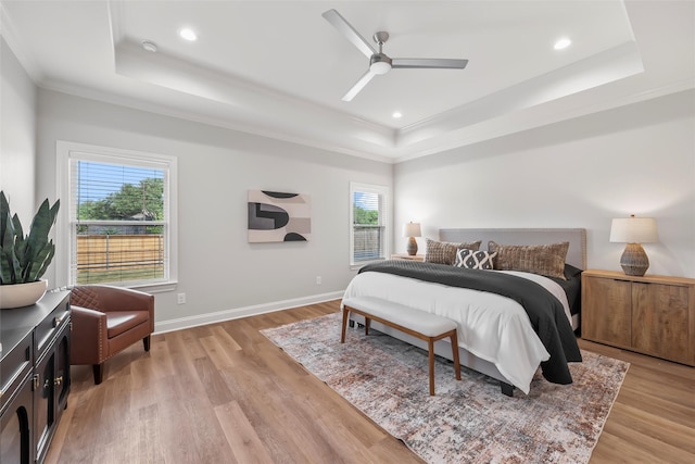 bedroom featuring a tray ceiling, light wood-style floors, and ornamental molding