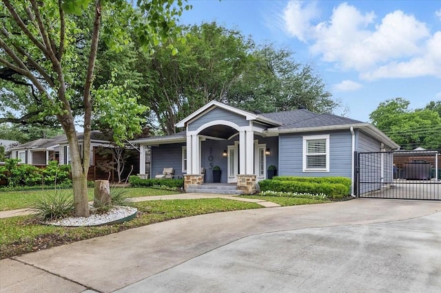 view of front of property featuring a gate, a porch, concrete driveway, and roof with shingles