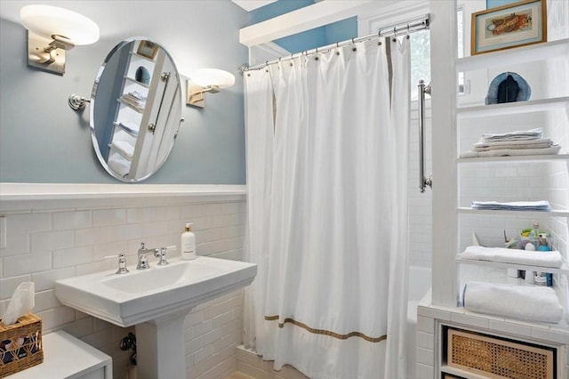 full bath with a sink, a shower with shower curtain, and tile walls