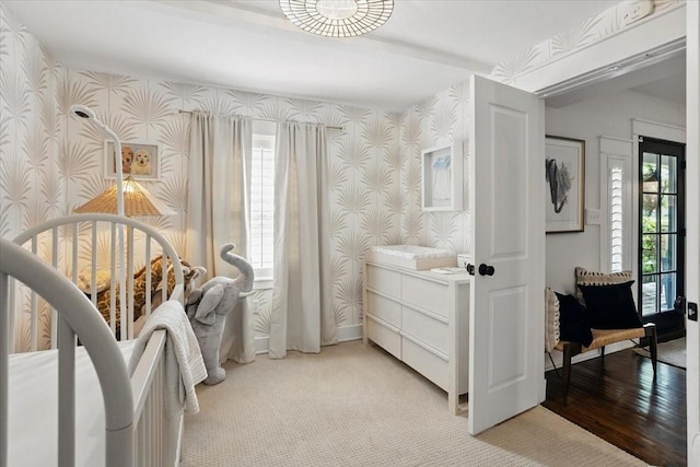 bedroom featuring baseboards, wallpapered walls, and light colored carpet