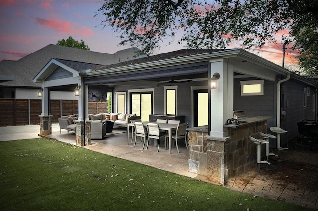 rear view of property featuring fence, a shingled roof, outdoor dry bar, a patio area, and outdoor lounge area