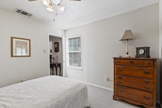 carpeted bedroom featuring a textured ceiling, visible vents, ceiling fan, and baseboards