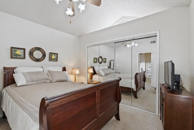 bedroom with a textured ceiling, a closet, light colored carpet, lofted ceiling, and visible vents