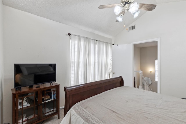 bedroom with a ceiling fan, visible vents, lofted ceiling, and a textured ceiling