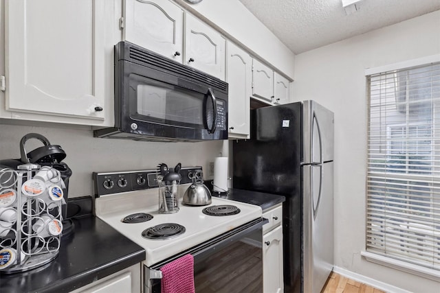 kitchen featuring black microwave, white cabinetry, electric range oven, and light wood-style flooring