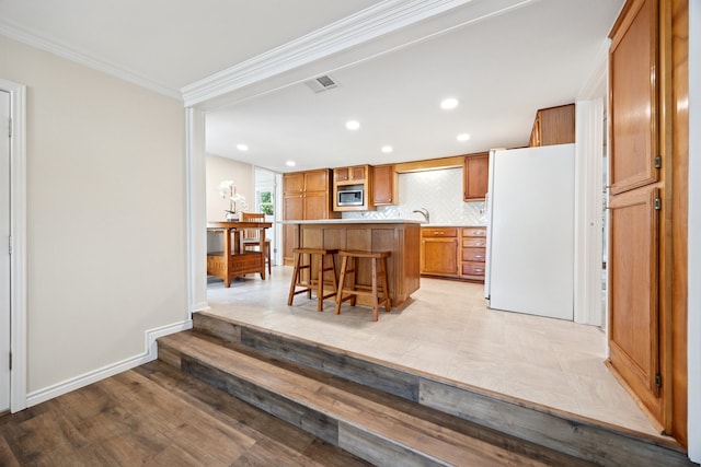 6725 Cahoba Dr, Fort Worth, TX 76135 - kitchen featuring a breakfast bar area, a kitchen island, visible vents, crown molding, and freestanding refrigerator