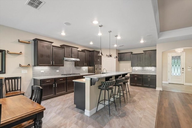 6514 Eagle Rock Dr, Frisco, TX 75036 - kitchen featuring stainless steel appliances, arched walkways, tasteful backsplash, visible vents, and under cabinet range hood